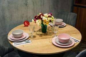 uma mesa de madeira com pratos e um vaso de flores em Arch Apart Hotel em Yerevan