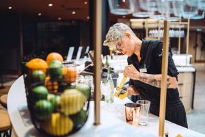a woman standing at a counter preparing a drink at Original Sokos Hotel Seurahuone Savonlinna in Savonlinna