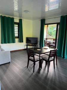 a living room with a table and chairs and a television at BUNGALOW F2 #Miti in Parea