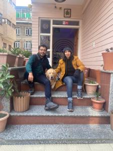 twee mensen en een hond zittend op de trappen van een huis bij Hotel Grand Aziz in Srinagar