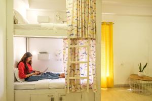 a woman sitting on a bunk bed with a laptop at Moustache Hostel, Jaipur in Jaipur