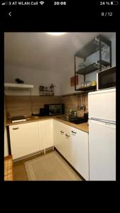 a kitchen with white cabinets and a white refrigerator at Tannenhof Apartment in Steinhaus am Semmering