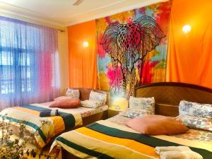 a bedroom with two beds and a painting on the wall at Ganga Vatika Boutique Hotel, Rishikesh in Rishīkesh