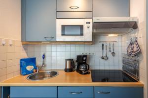eine Küchentheke mit einer Spüle und einer Mikrowelle in der Unterkunft Haus Holstein - WG 6 mit Balkon, strandnah in Ostseebad Sellin
