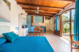 a bedroom with a blue bed and a kitchen at Beach Room Apartment in Quartu SantʼElena