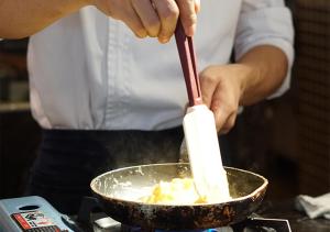 a person cooking food in a pan with a spatula at Crowne Plaza Nanchang Riverside, an IHG Hotel in Nanchang