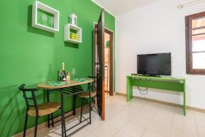 Habitación verde con mesa y TV en Jungle Room Apartment, en Quartu SantʼElena