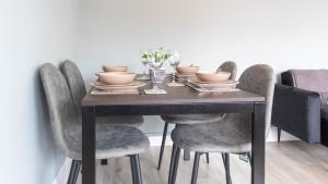 a dining room table with gray chairs and a table with dishes at Blairmuire House in Broxburn
