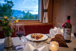 een tafel met een bord eten en een fles wijn bij Luxury and Nature House Moarlhof in Castelrotto