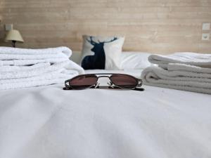 un par de gafas de sol sentadas en la parte superior de una cama en Hôtel L'Oustalet en Font Romeu Odeillo Via