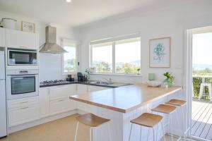 a kitchen with white cabinets and a counter with stools at The Bay House in Albany