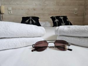 une paire de lunettes de soleil assise sur un lit et des serviettes dans l'établissement Hôtel L'Oustalet, à Font-Romeu-Odeillo-Via