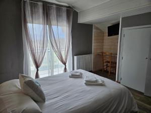 una camera da letto con un letto bianco e una grande finestra di Hôtel L'Oustalet a Font-Romeu-Odeillo-Via