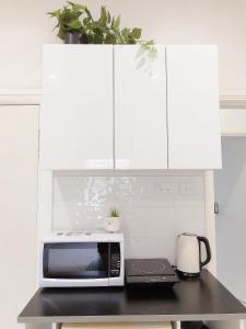 Una cocina con gabinetes blancos y un microondas en una encimera. en Serene Double Studio - Mins to Station & UNSW, en Sídney