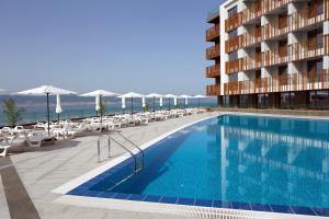 einem Pool vor einem Gebäude mit Stühlen und Sonnenschirmen in der Unterkunft Paradiso Dreams Hotel in Nessebar