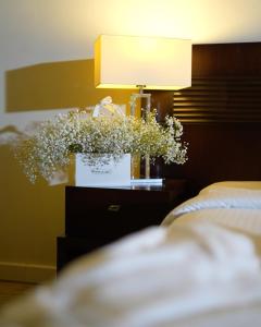 a nightstand with a lamp and a bouquet of flowers at The Parisian Hotel in Beirut