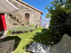 a garden with a red door and a stone house at Maison à la campagne Les Oliviers in La Bruffière