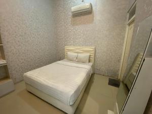 Dormitorio pequeño con cama blanca y aire acondicionado en Griya RW Family Guest House Redpartner, en Solo