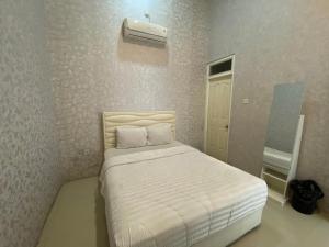 1 dormitorio pequeño con 1 cama con sábanas blancas en Griya RW Family Guest House Redpartner, en Solo