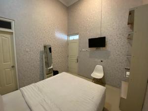 sypialnia z białym łóżkiem i telewizorem w obiekcie Griya RW Family Guest House Redpartner w mieście Surakarta