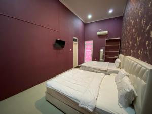 una camera con due letti e una parete viola di Griya RW Family Guest House Redpartner a Solo