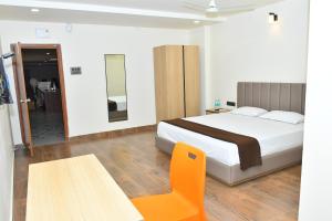 a bedroom with a bed and a table and a chair at SWAGATH RESIDENCY in Devarkonda