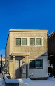 a brick building with a door in the snow at 新屋 札幌市中心薄野車程5分 廁所x2 浴室x1 可停車2台 高速Wi-Fi 對街超商 in Sapporo