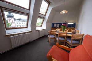 een eetkamer met een tafel, stoelen en ramen bij IT Centrum Apartments in Vrchlabí