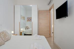 a white bedroom with a bed and a mirror at La Casetta Bianca in Loiri