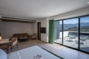 a living room with a couch and a balcony at Velmore Kasauli Operated by Royal Orchid Hotel Ltd. in Kasauli
