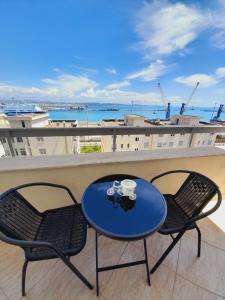 都拉斯Port View Condo的阳台配有一张蓝色的桌子和两把椅子