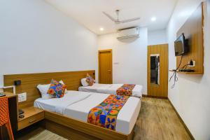 a hotel room with two beds and a television at FabExpress Anurag Residency in Guwahati
