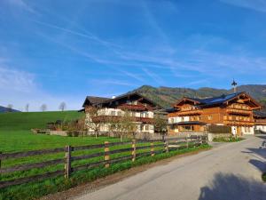 a large wooden house with a fence next to a field at Appartment Ransburggut in Flachau