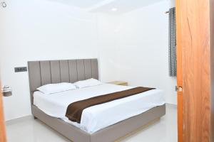 a bed with white sheets and a brown blanket at SWAGATH RESIDENCY in Devarkonda