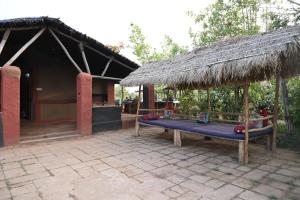 a picnic table in front of a hut with a thatch roof at Bastar Birds Nest 