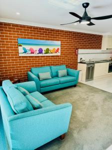 una sala de estar con 2 sofás azules y una pared de ladrillo en The Roseville Apartments, en Tamworth