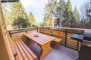 Rogla Alpina Residence في زريس: طاولة خشبية ومقعد على سطح مع أشجار