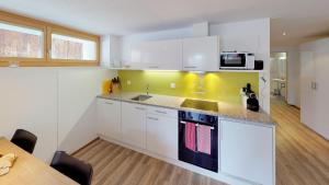 a kitchen with white cabinets and a sink and a table at Chasa Samalgors in Tschlin 