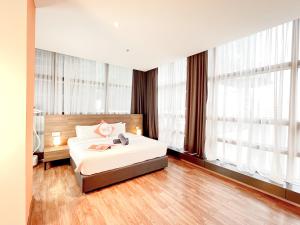 una camera da letto con un letto con lenzuola bianche e finestre di The Lonsdale - Bangsar Trade Centre a Kuala Lumpur