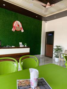 eine grüne Wand in einem Restaurant mit Tisch und Stühlen in der Unterkunft JP Hotel in Tezpur