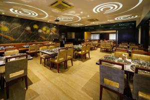 a restaurant with tables and chairs in a room at Hotel Celebration in Jamnagar