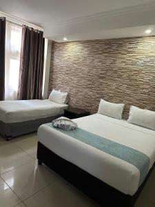 Habitación de hotel con 2 camas y pared de ladrillo en Bayside Hotel 14 Monty Naicker(Pinestreet), en Durban