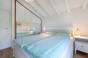 um quarto branco com uma cama grande e lençóis azuis em Perla Azzurra mit Seezugang em Toscolano Maderno