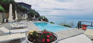 萊萬托的住宿－Hotel La Giada del Mesco，一个带椅子和遮阳伞的游泳池以及大海