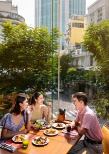 un grupo de personas sentadas en una mesa comiendo comida en Sheraton Saigon Grand Opera Hotel, en Ho Chi Minh