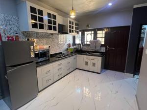 una cucina con armadietti bianchi e pavimento piastrellato bianco di Haven Retreat a Srinagar