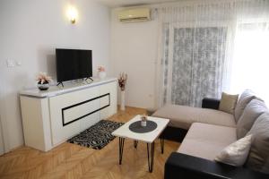 ein Wohnzimmer mit einem Sofa und einem Flachbild-TV in der Unterkunft Apartments Kresan in Zadar