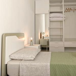 Habitación blanca con cama y espejo en Living Castro Apartments, en Castro di Lecce