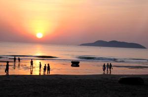 eine Gruppe von Menschen, die bei Sonnenuntergang am Strand stehen in der Unterkunft Khách sạn Xuân Dương in Cửa Lô