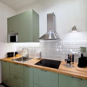 una cocina con armarios verdes y fregadero en Living Castro Apartments, en Castro di Lecce